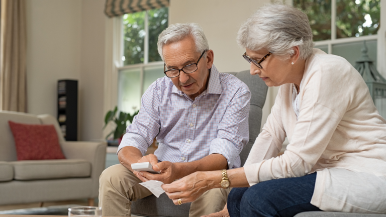 A couple sits at a table with tax documents spread out, attentively reviewing their 2025 tax returns. A financial advisor from Greenville, SC, sits across from them, providing guidance.