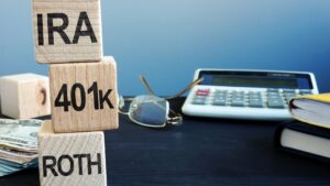 Wooden blocks labeled 401(k) and Roth IRA representing different retirement savings options available in 2025