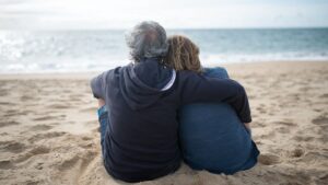Retired couple sitting peacefully on the beach, symbolizing long-term financial planning and retirement success