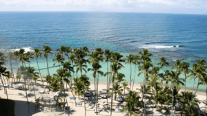 Scenic view of a tropical Jamaican beach with turquoise water, palm trees, and lounge chairs—highlighting a travel spotlight from BCA Private Wealth’s weekly newsletter, encouraging clients to explore and unwind.
